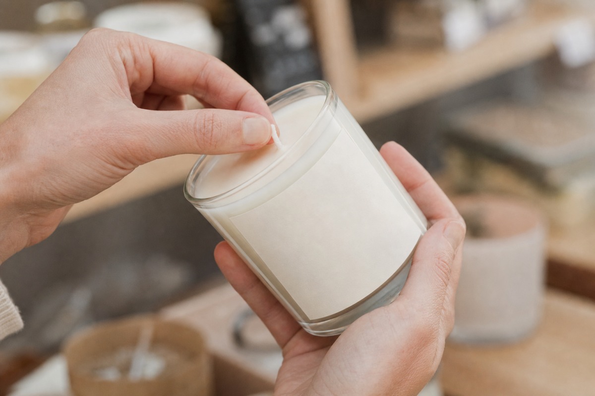 Hands inspecting a cotton wick and a blank candle label before buying in a shop