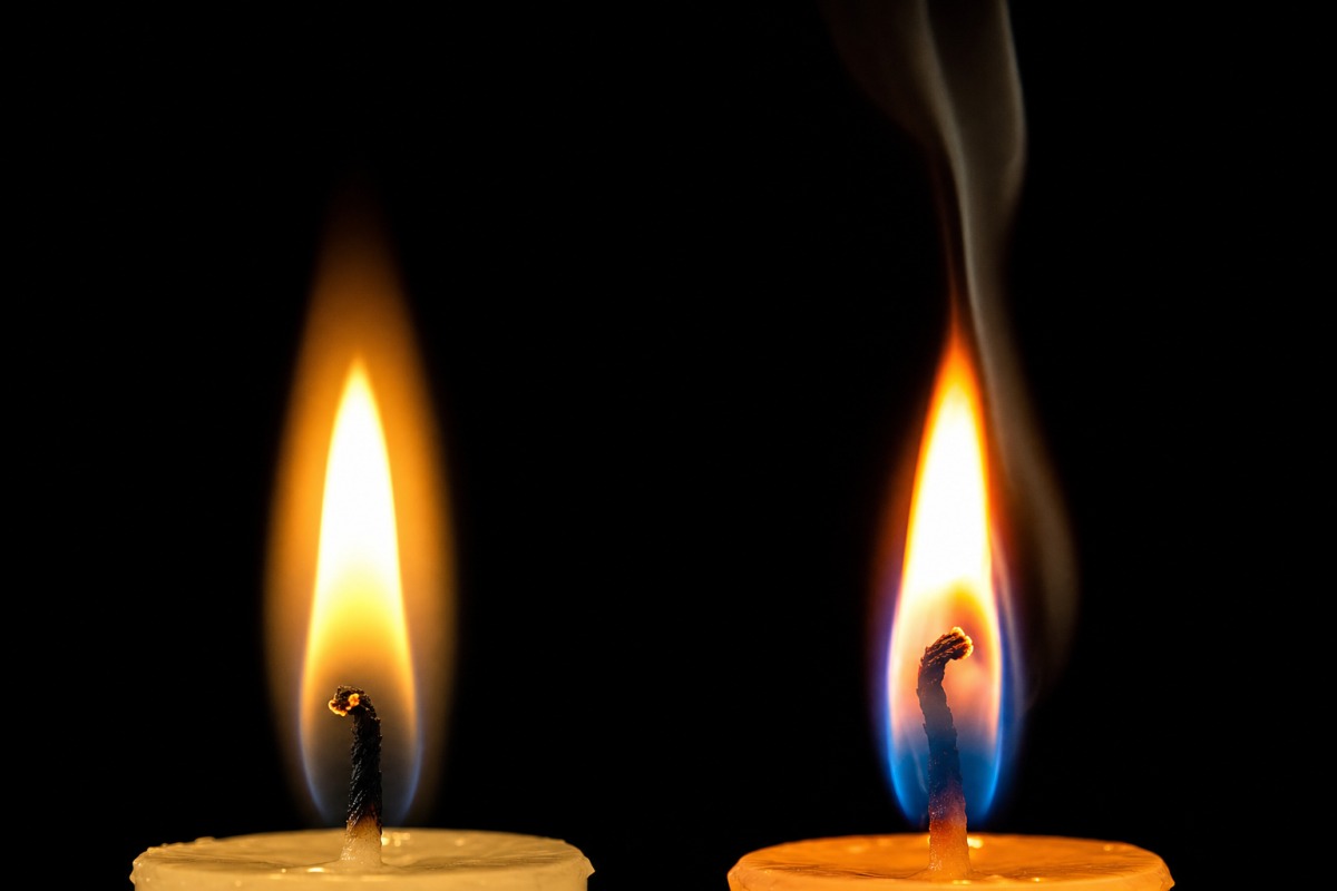 Two flames side by side — a clean natural flame on the left, a smoking paraffin flame on the right